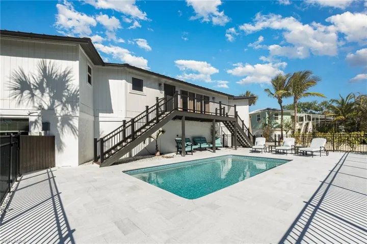 Exterior featuring a rectangular pool with a mosaic tile interior, surrounded by light-toned paver decking