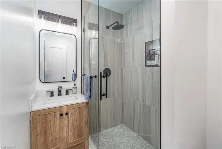 Contemporary bathroom featuring a glass-enclosed shower with gray tile walls and a hexagonal tile floor