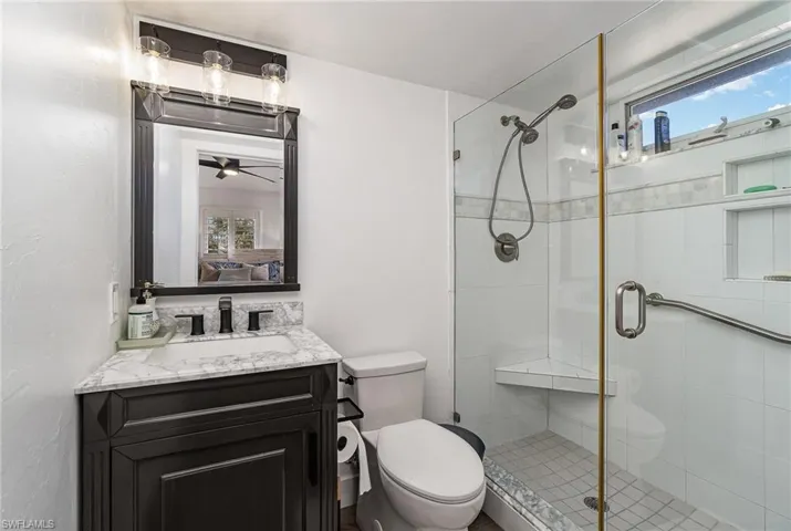 Bathroom featuring a glass-enclosed shower with a built-in bench and a window