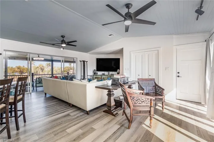 Open-concept living area featuring wood-finish flooring, a light blue beadboard ceiling, and multiple ceiling fans