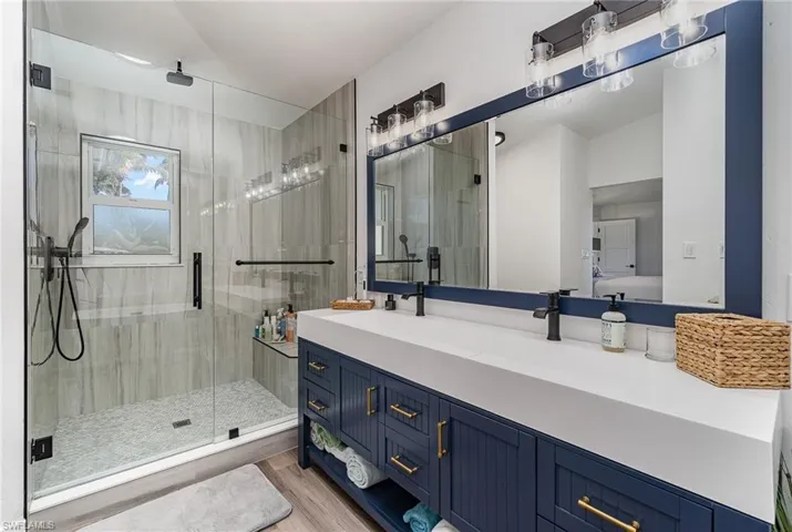 Contemporary bathroom featuring a spacious glass-enclosed shower with tile surround, a built-in shower niche, and a window