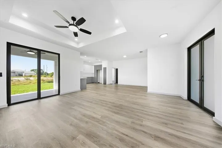 Unfurnished living room featuring a raised ceiling, light wood-type flooring, and recessed lighting