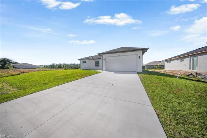View of front of property featuring a front lawn, driveway, and a garage