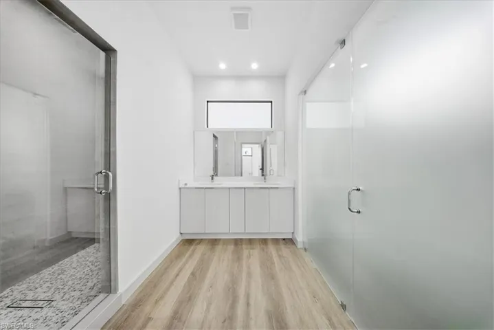 Full bath with a stall shower, double vanity, and light wood-type flooring