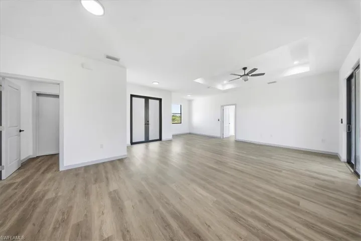 Unfurnished living room featuring a tray ceiling, light wood finished floors, a ceiling fan, and recessed lighting