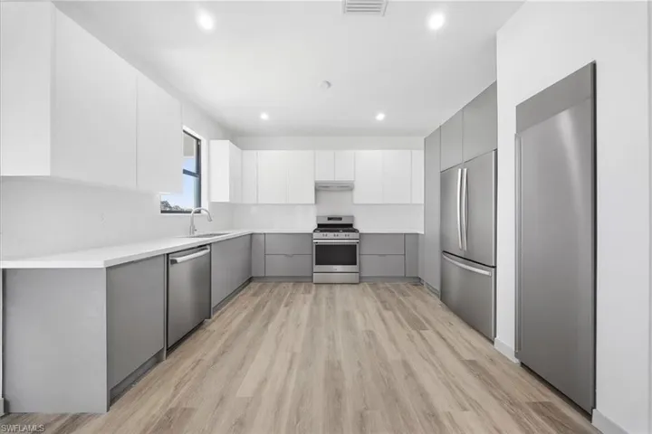 Kitchen featuring gray cabinetry, stainless steel appliances, modern cabinets, light wood-type flooring, and recessed lighting