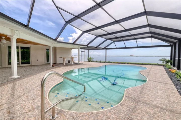 View of swimming pool with a water view, a patio, glass enclosure, and ceiling fan
