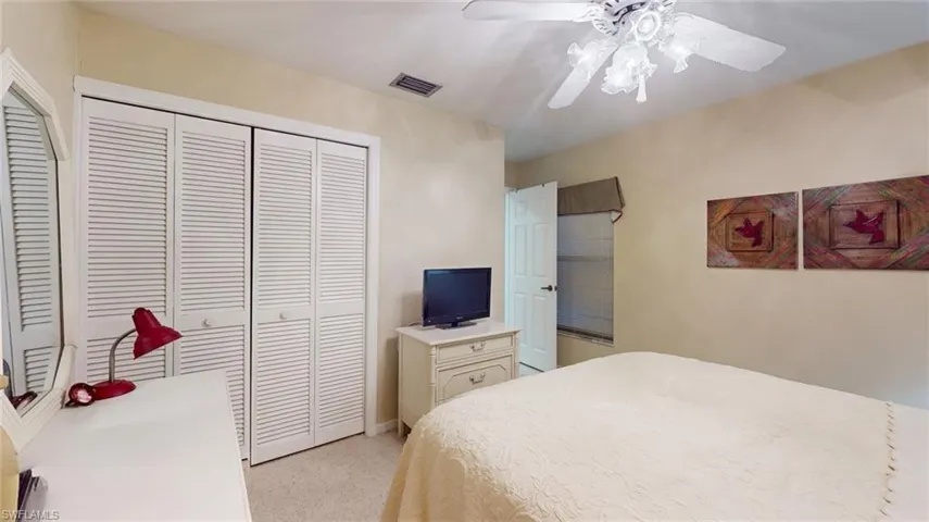 Carpeted bedroom featuring ceiling fan and a closet