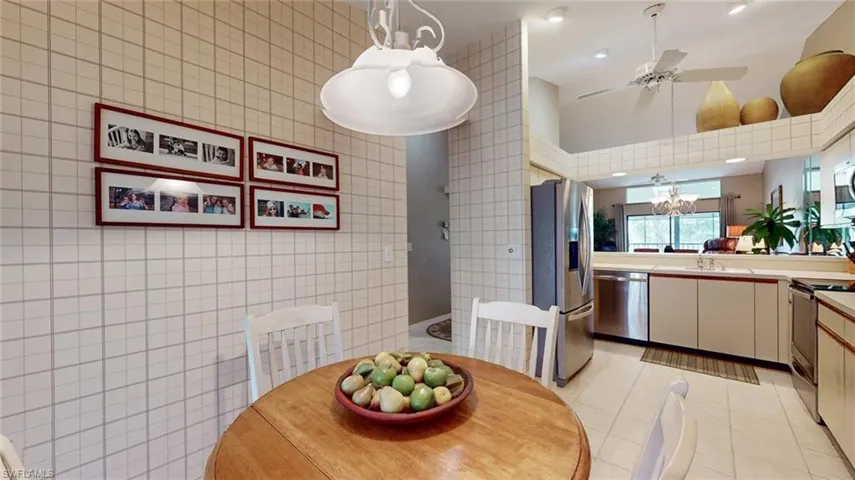 Dining space featuring tile walls, sink, light tile floors, and ceiling fan with notable chandelier