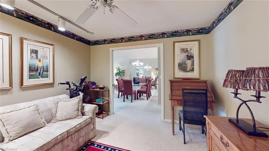 Carpeted living room with ceiling fan with notable chandelier