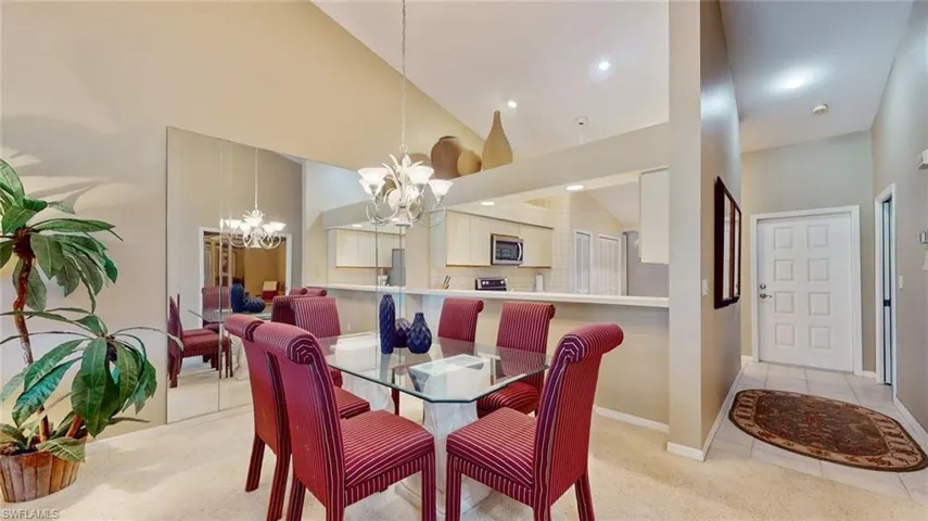 Dining area featuring a notable chandelier, high vaulted ceiling, and light colored carpet