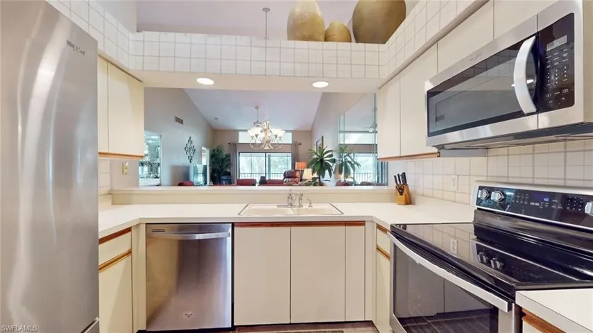 Kitchen featuring lofted ceiling, stainless steel appliances, backsplash, a chandelier, and sink