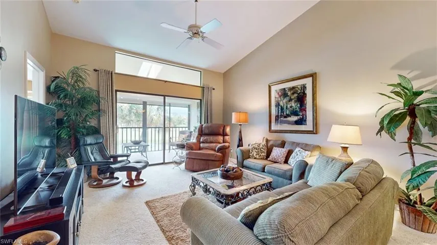 Living room with high vaulted ceiling, carpet floors, and ceiling fan