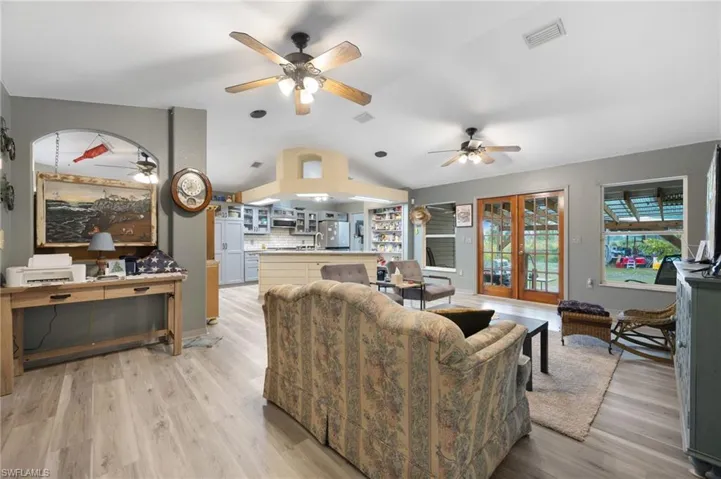 Living area featuring french doors, a ceiling fan, lofted ceiling, and light wood-style floors