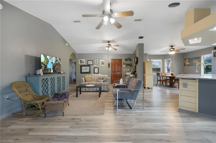 Living area with vaulted ceiling, light wood-style flooring, and a ceiling fan