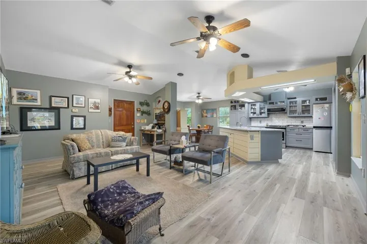 Living area with vaulted ceiling, light wood finished floors, and ceiling fan