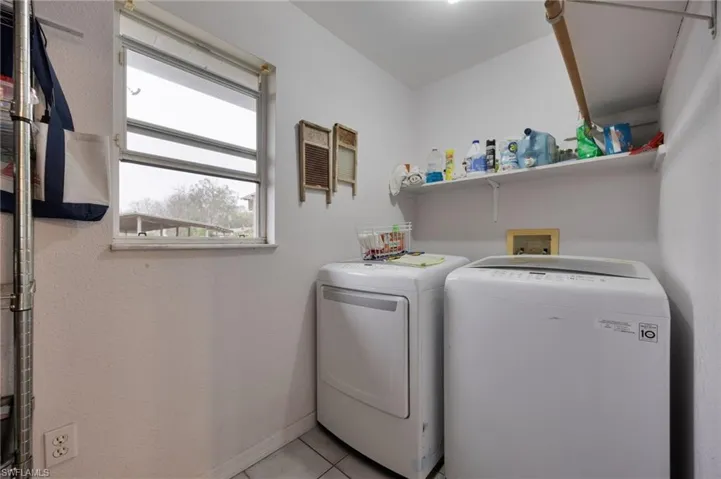 Laundry area with light tile patterned flooring and washing machine and clothes dryer