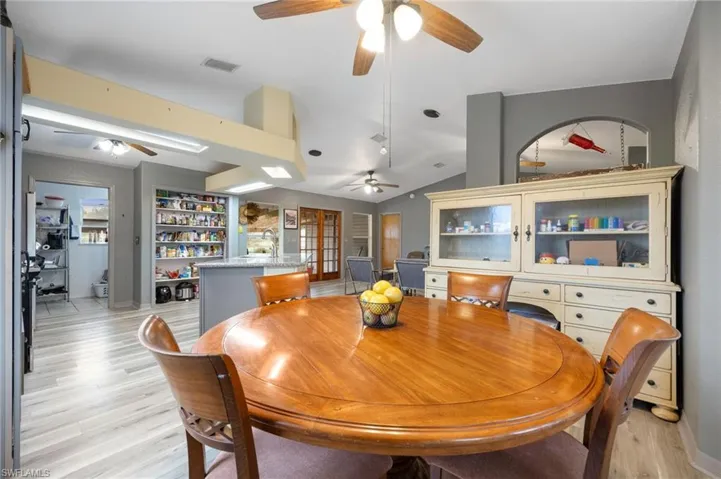 Dining space with light wood-style flooring, lofted ceiling, and built in shelves