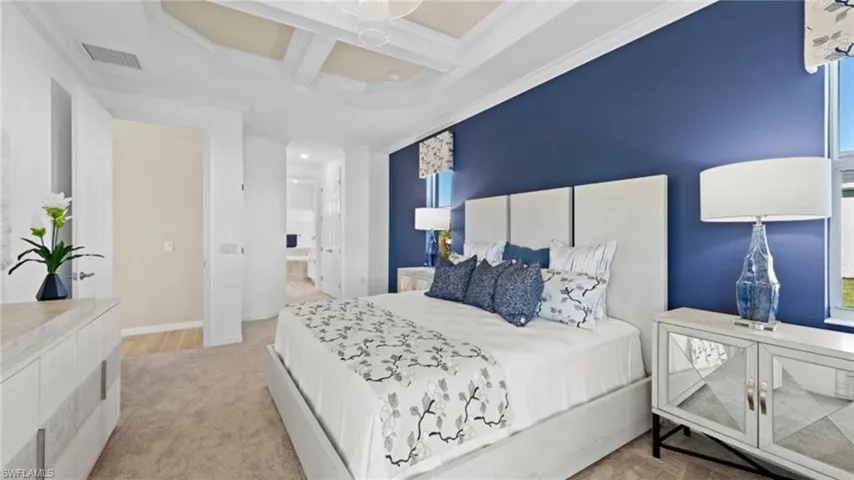 Carpeted bedroom with ornamental molding, coffered ceiling, and visible vents