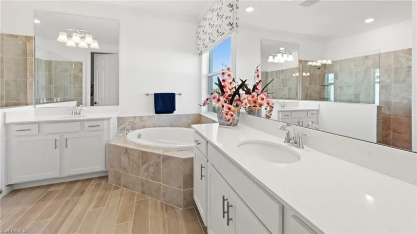 Bathroom featuring a sink, crown molding, a garden tub, and a walk in shower