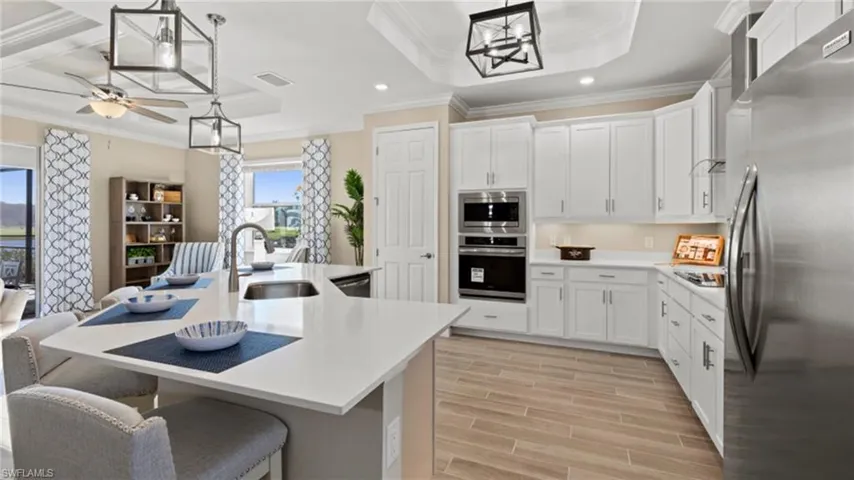 Kitchen featuring light countertops, a sink, stainless steel appliances, wood tiled floor, and visible vents