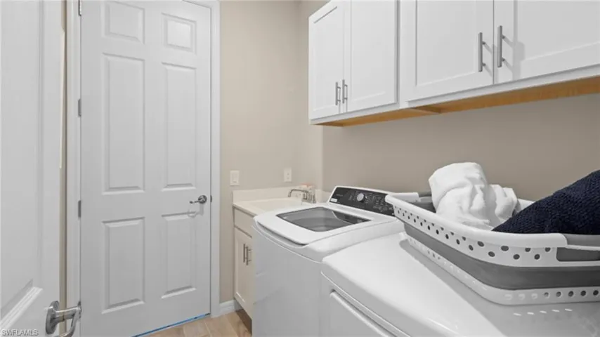 Washroom with light wood-style flooring, a sink, cabinet space, and washing machine and dryer
