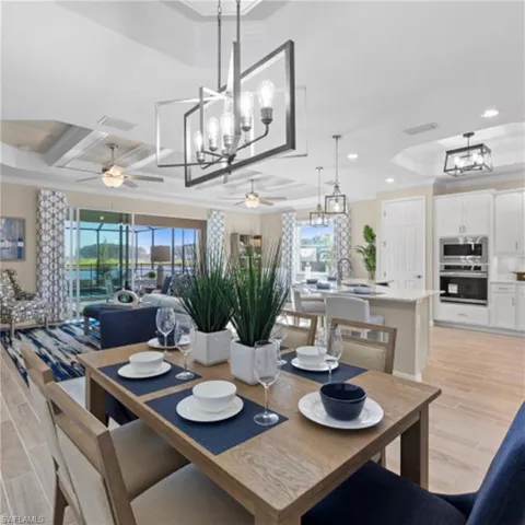 Dining area with visible vents, light wood-style floors, and ceiling fan with notable chandelier