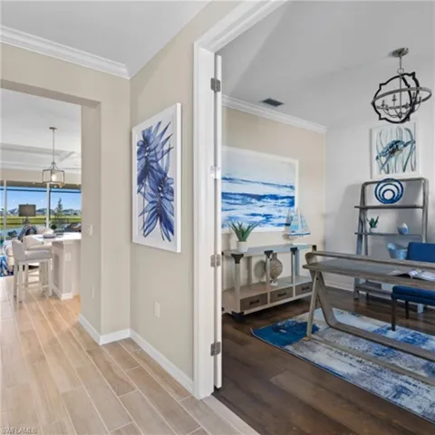 Hallway featuring visible vents, light wood finished floors, baseboards, ornamental molding, and an inviting chandelier