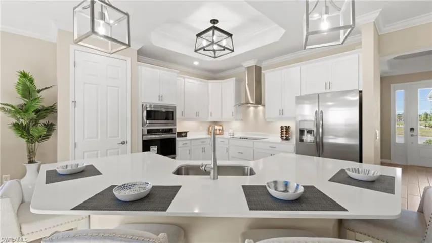 Kitchen featuring crown molding, a breakfast bar, wall chimney exhaust hood, stainless steel appliances, and a sink