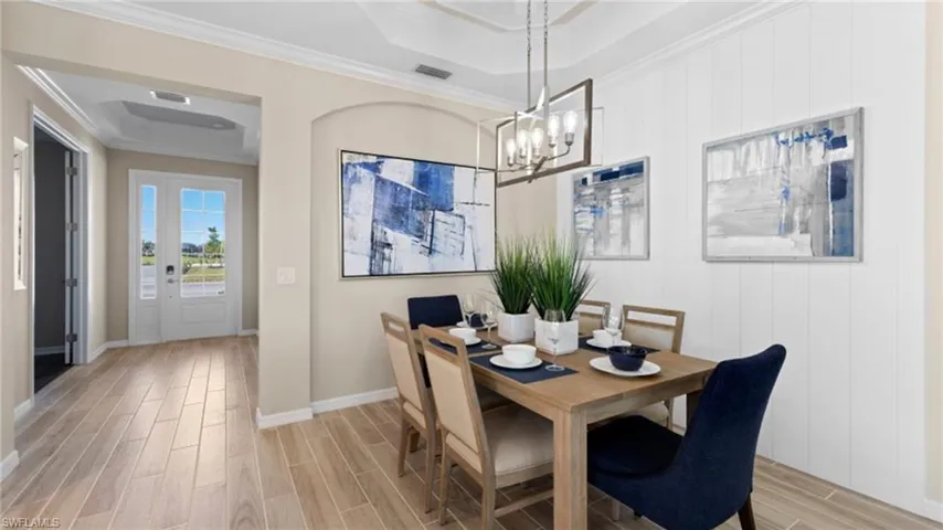 Dining area with visible vents, crown molding, baseboards, wood finish floors, and an inviting chandelier