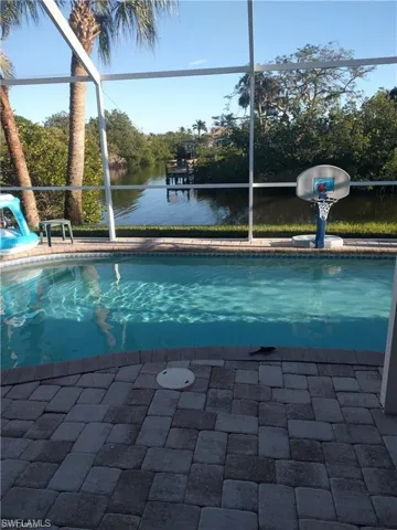 View of pool featuring a water view and glass enclosure