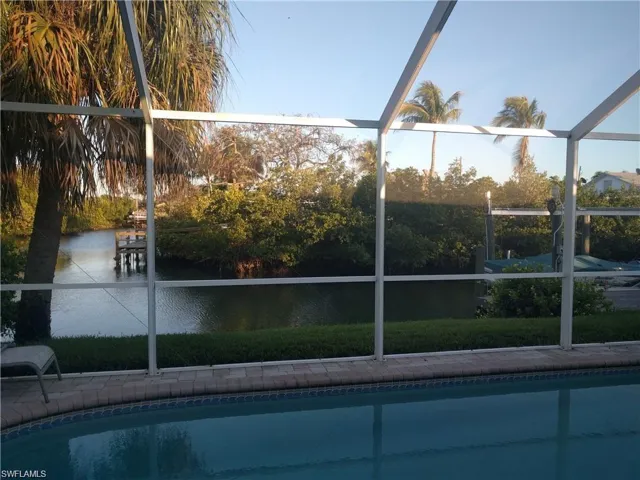 View of swimming pool with a water view and glass enclosure