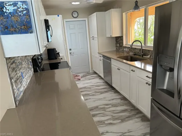 Prior to Milton.  Kitchen featuring decorative backsplash, white cabinets, stainless steel appliances, and sink