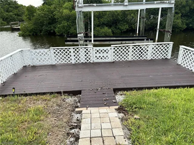 Wooden deck with a boat lift and a water view.