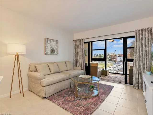 Living area featuring neutral tile flooring and large black-framed glass sliding doors opening to an outdoor balcony