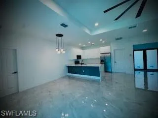 Kitchen with open floor plan, a peninsula, light countertops, recessed lighting, and stainless steel fridge