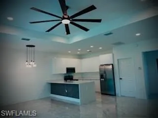 Kitchen featuring recessed lighting, freestanding refrigerator, white cabinets, a peninsula, and light countertops