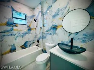 Full bathroom with bathtub / shower combination, vanity, and stone wall