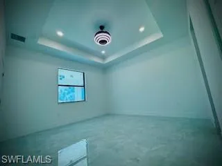 Empty room featuring a raised ceiling, recessed lighting, and concrete floors
