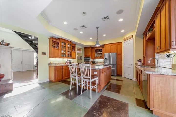 Kitchen with appliances with stainless steel finishes, a breakfast bar, sink, a kitchen island, and hanging light fixtures