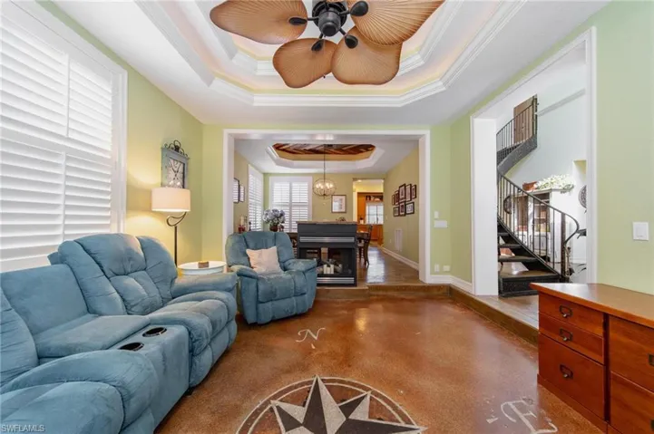 Living room with a tray ceiling, ceiling fan, and crown molding