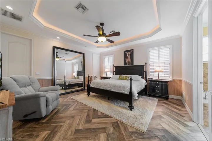 Bedroom with ceiling fan, a raised ceiling, and parquet flooring
