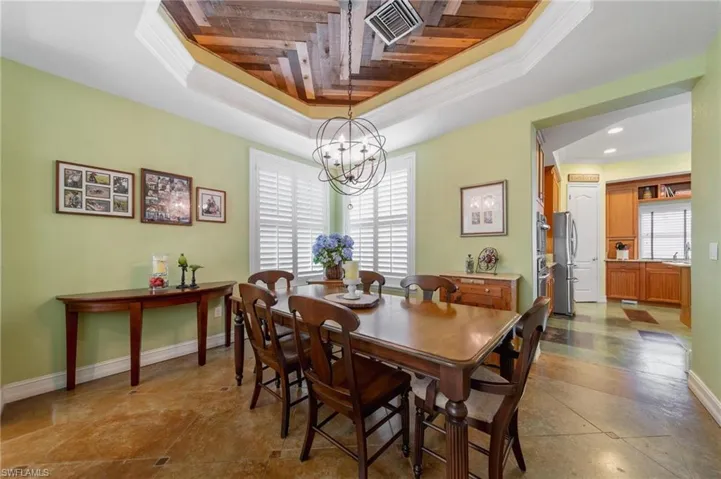 Dining area featuring a tray ceiling, ornamental molding, wood ceiling, and a notable chandelier