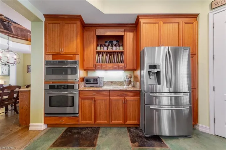 Kitchen with dark hardwood / wood-style flooring, appliances with stainless steel finishes, and an inviting chandelier