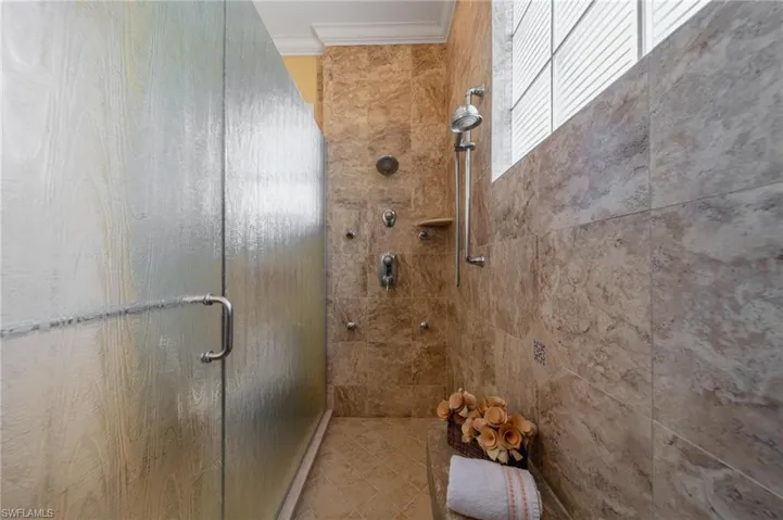 Bathroom with crown molding and an enclosed shower