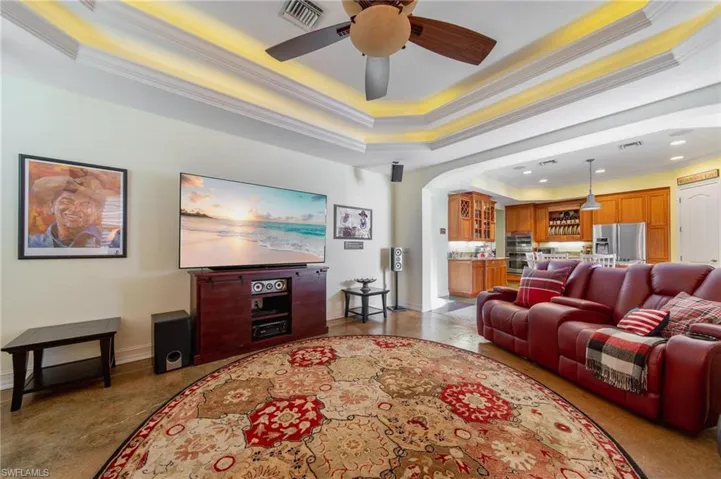 Living room featuring a raised ceiling, ceiling fan, and ornamental molding