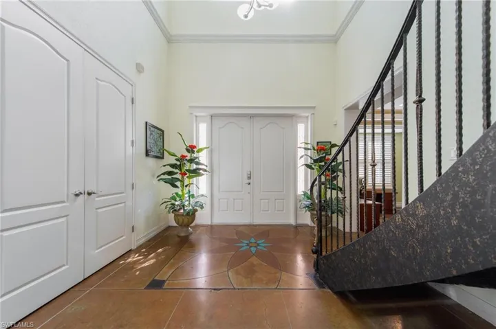 Tiled foyer featuring a towering ceiling and ornamental molding