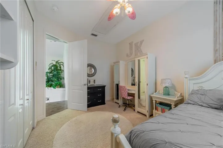Carpeted bedroom with ceiling fan and a closet