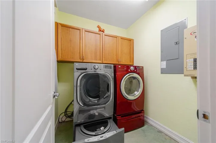 Clothes washing area with cabinets, separate washer and dryer, and electric panel