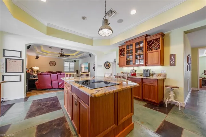Kitchen with black electric stovetop, ornamental molding, a tray ceiling, ceiling fan, and a center island